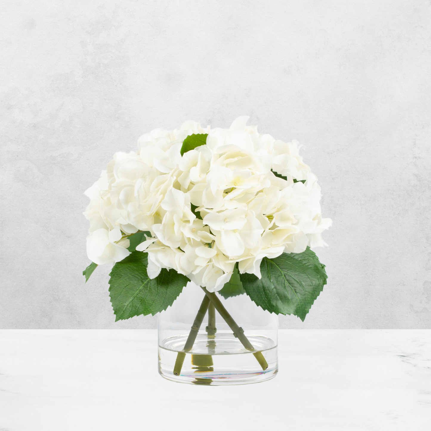 Faux hydrangea centerpiece arrangement in glass vase
